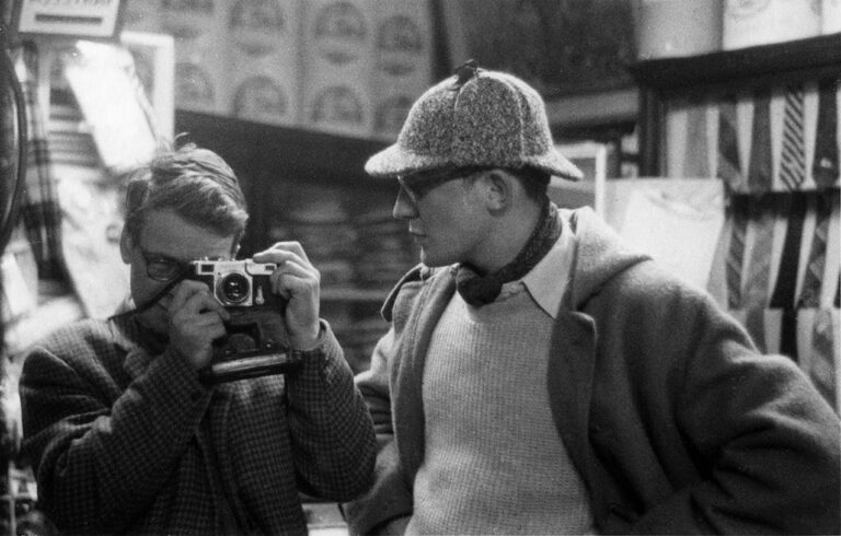 black and white photograph of the photographer in a mirror with a man next to him wearing a hat